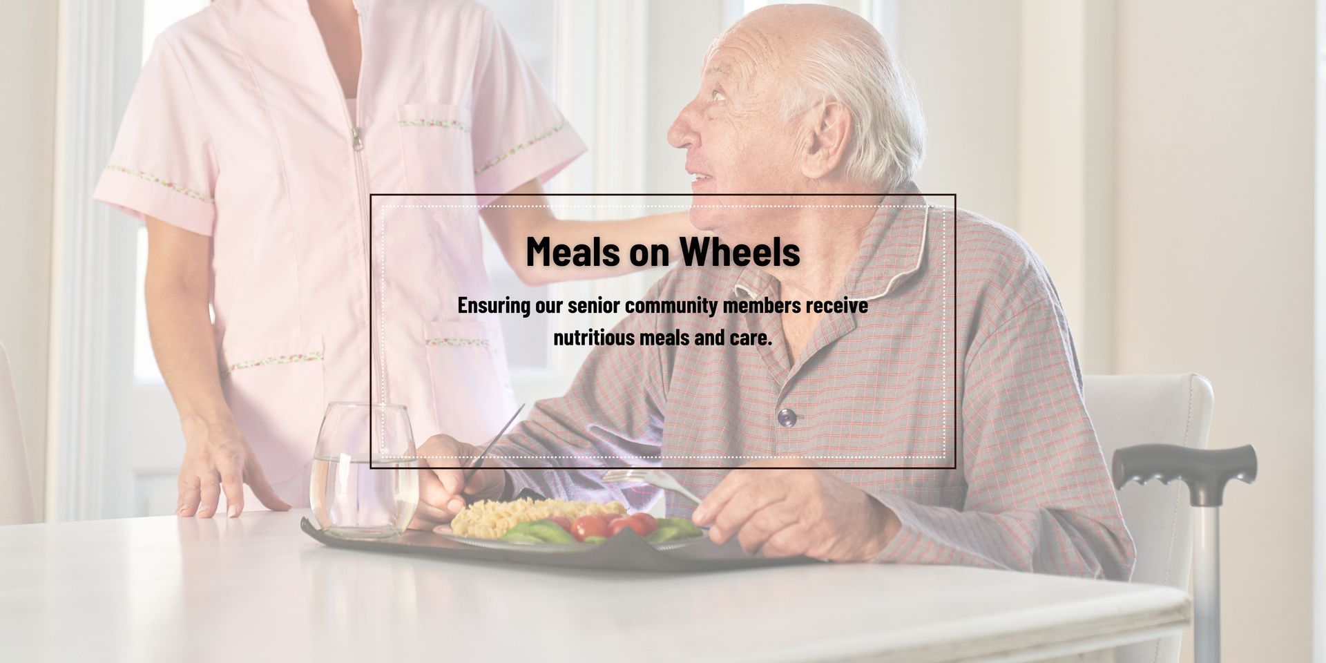 An elderly man is sitting at a table with a nurse serving him food.