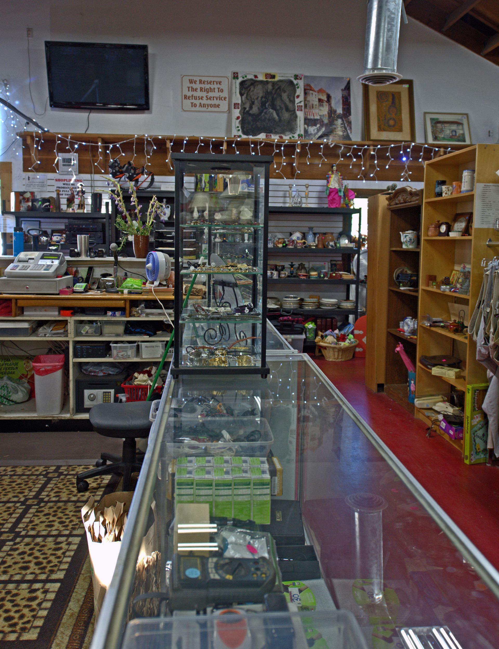 A display case in a store with a tv on the wall above it